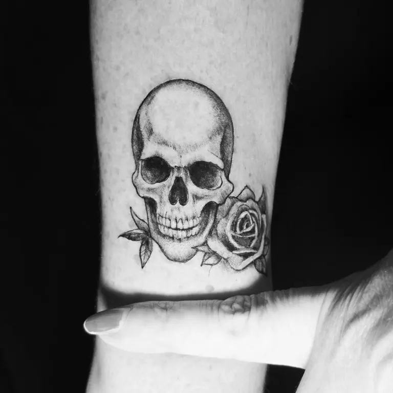 Tatuaggio di teschio e rosa sul polpaccio.