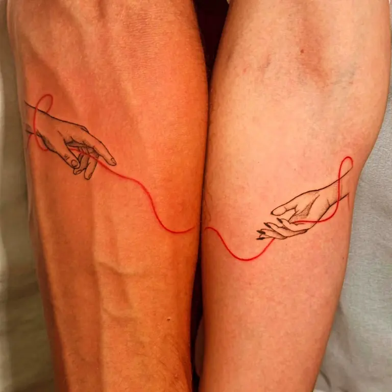 Due tatuaggi correlati su avambracci affiancati con mani e filo rosso.