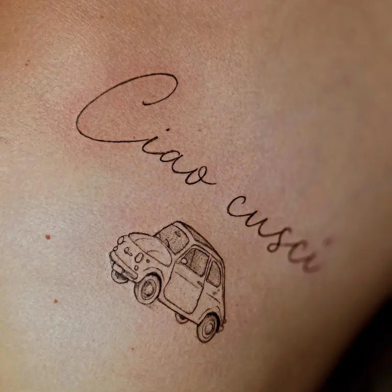 Piccola automobile con lettering Ciao cuscù tatuata su un arto.