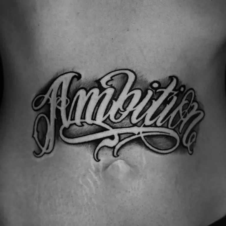 Lettering ornamentale Ambition tatuato sul braccio.