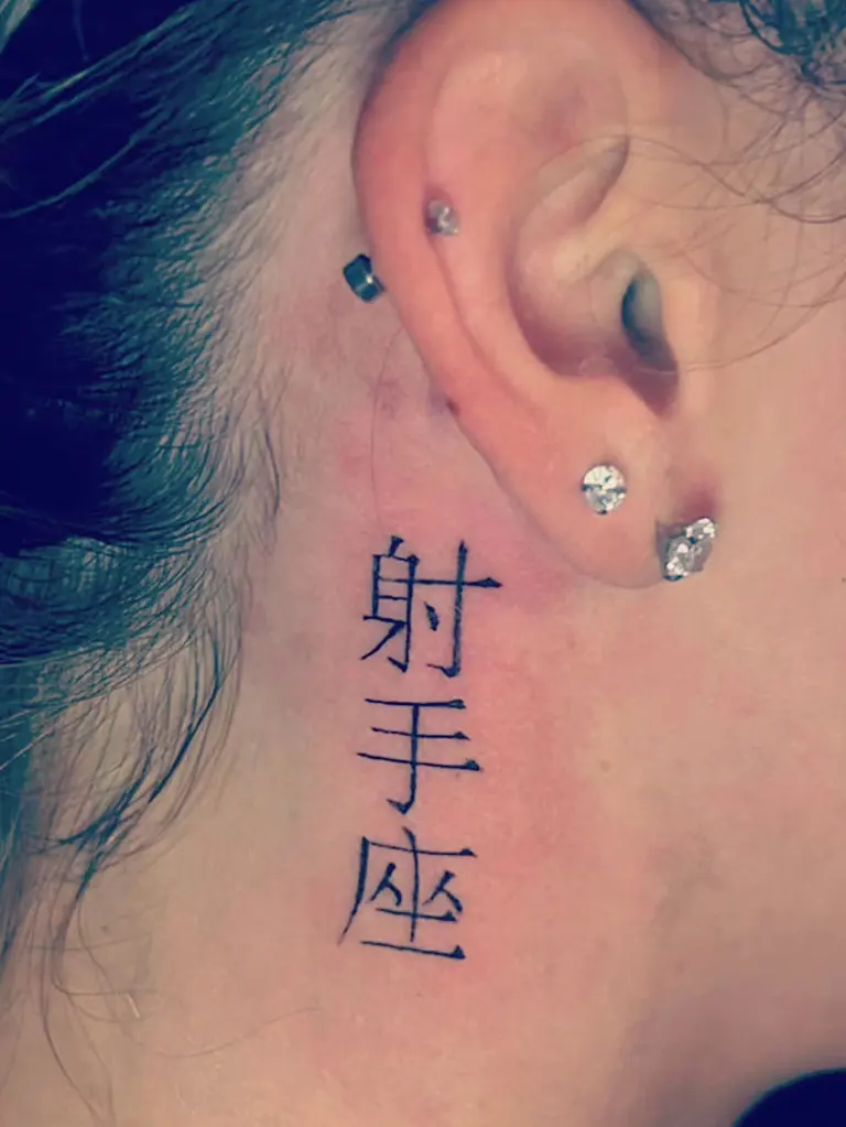 Caratteri giapponesi tatuati dietro l’orecchio.