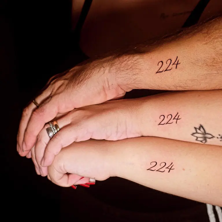 Tre piccoli tatuaggi numerici su tre polsi affiancati.
