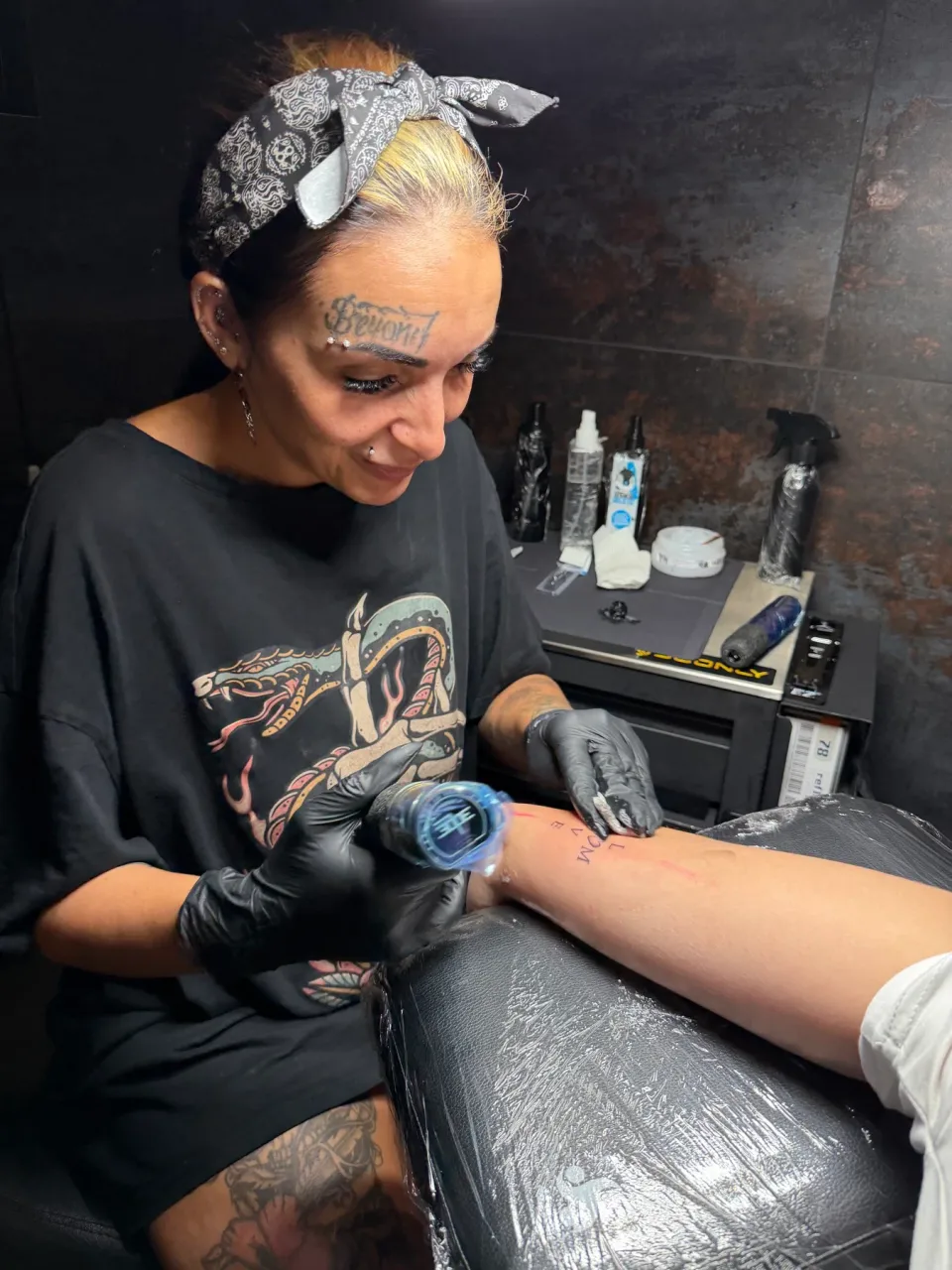 Jamila mentre tatua un avambraccio nello studio.